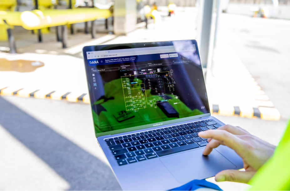 Schermo di laptop con interfaccia DANA di Italgas per controllo rete gas, sfondo industriale.