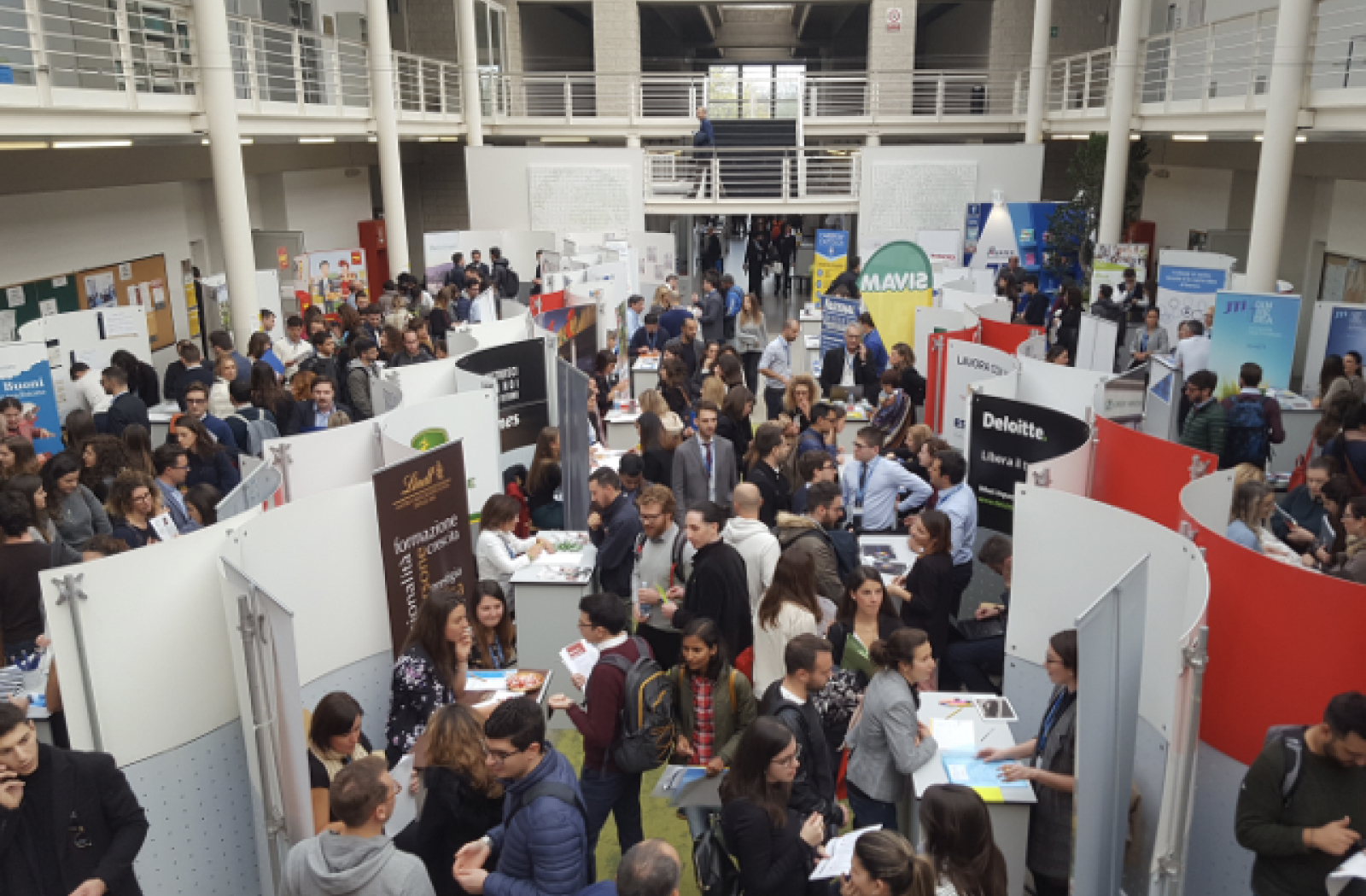 L'immagine mostra un evento di orientamento professionale affollato, al quale partecipa anche Italgas con uno stand, insieme a numerose altre aziende.