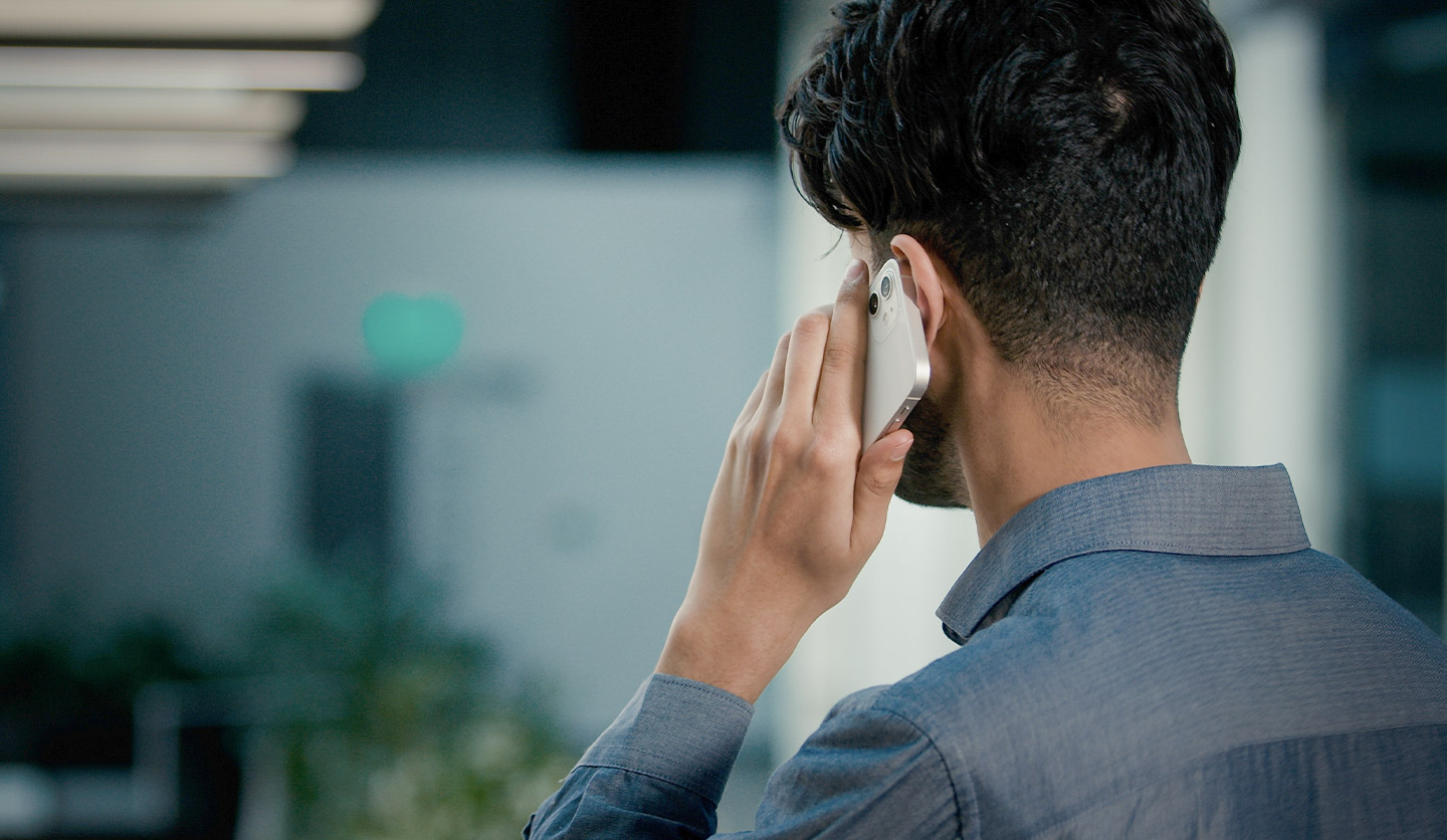 Uomo in ufficio parla al telefono, possibile intervista di lavoro per Italgas. Ambiente professionale.