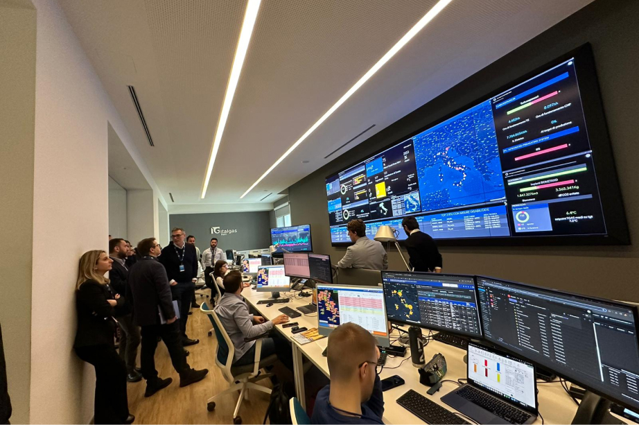 Group of people observing screens in a modern control room with Italgas branding.