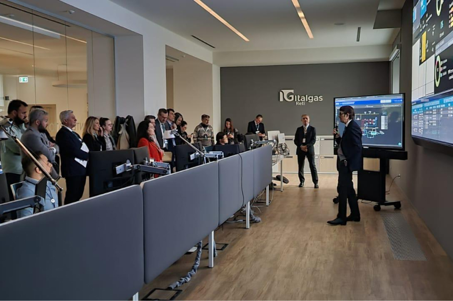 Personale Italgas in sala controllo con schermi dati e presentazione.