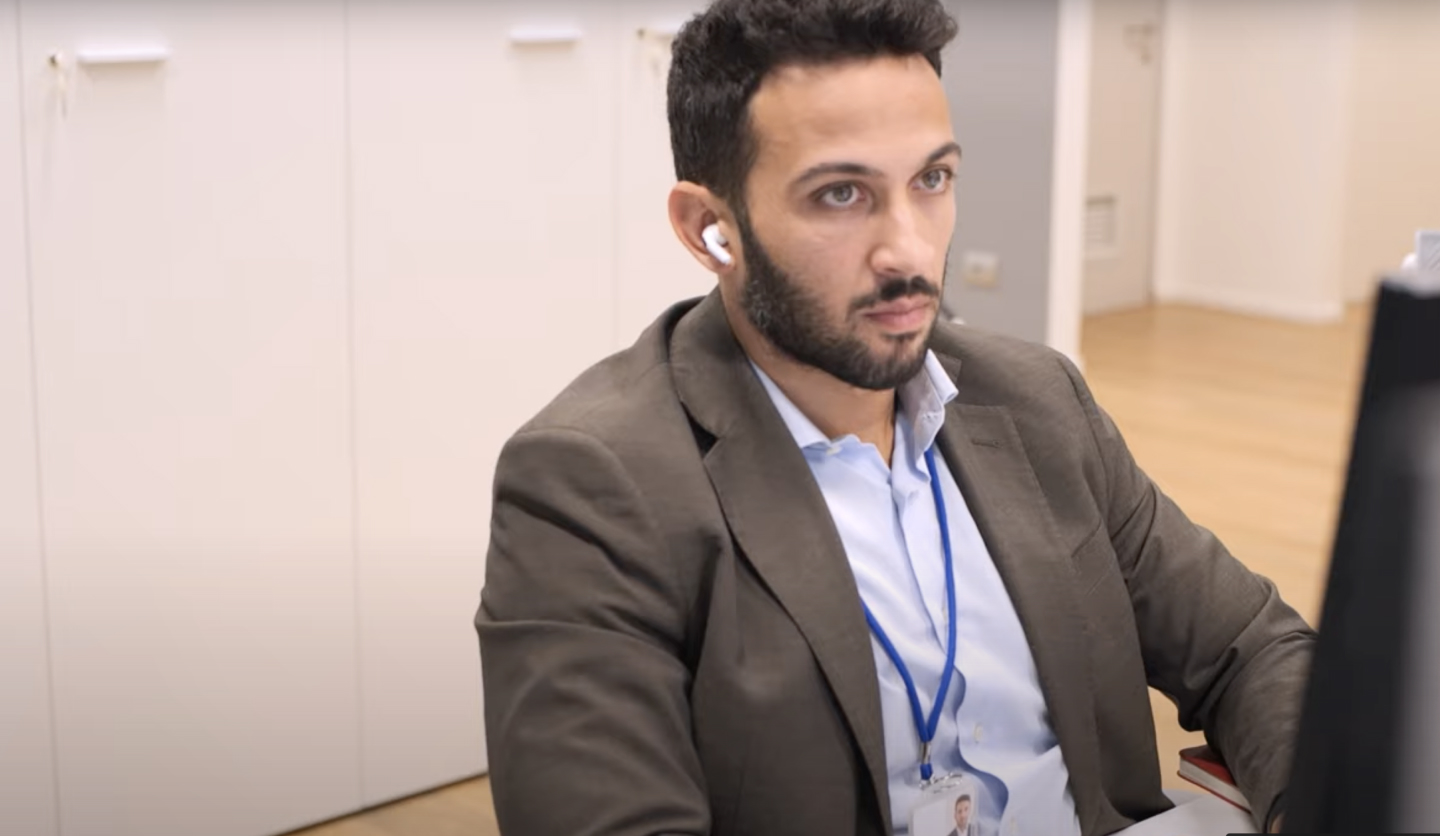 Un uomo in giacca e auricolari lavora su un computer in ufficio Italgas come Responsabile Analytics & AI.