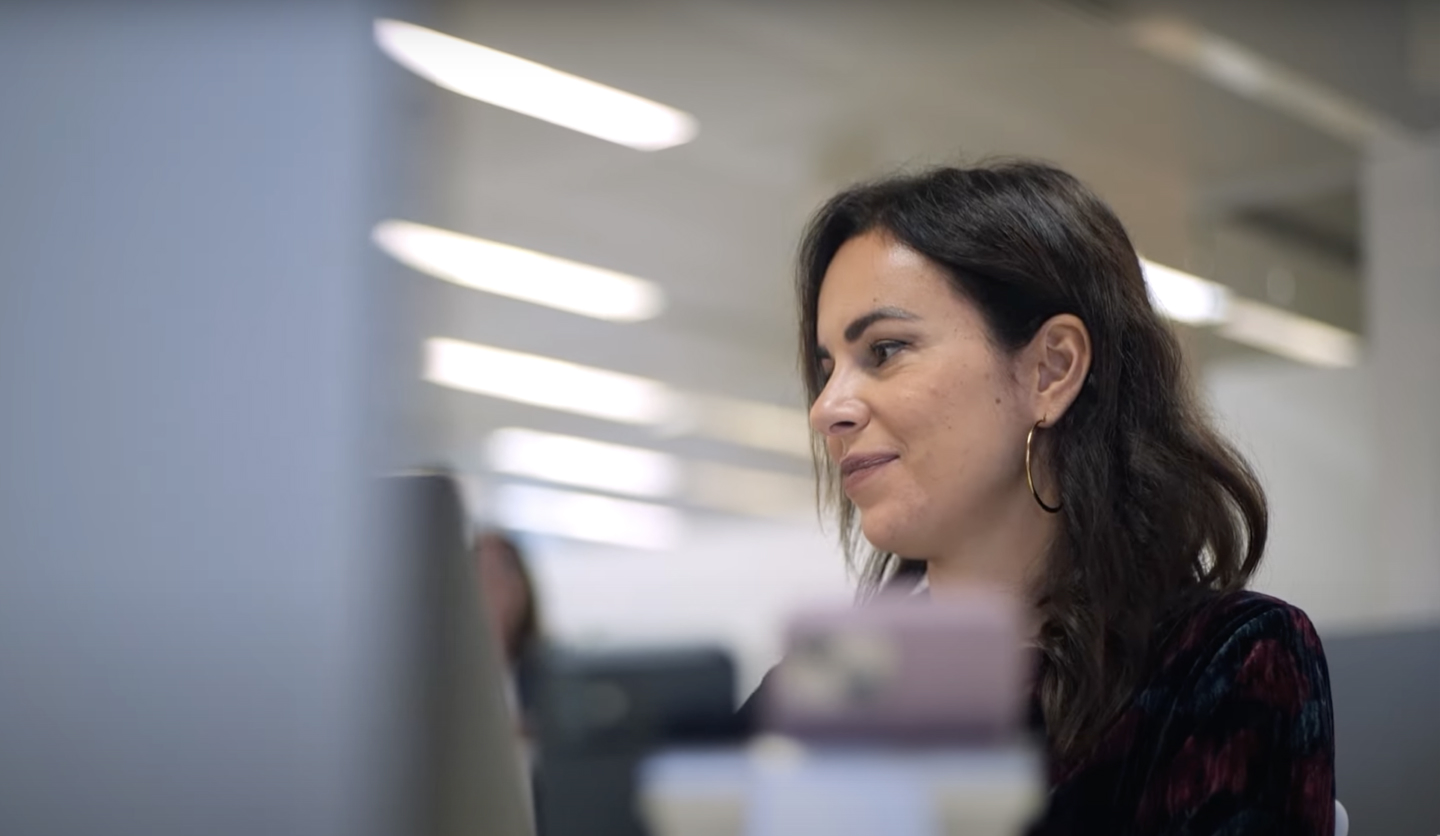 Donna sorride davanti a monitor in ufficio, rappresenta Italgas nel settore compliance.