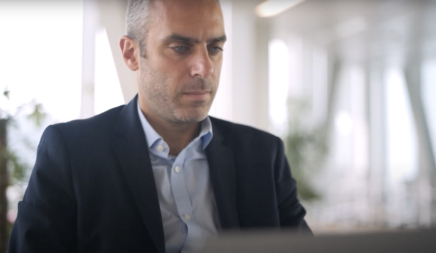 Uomo in abito lavora al computer in ufficio luminoso rappresentando Italgas nel settore new business.