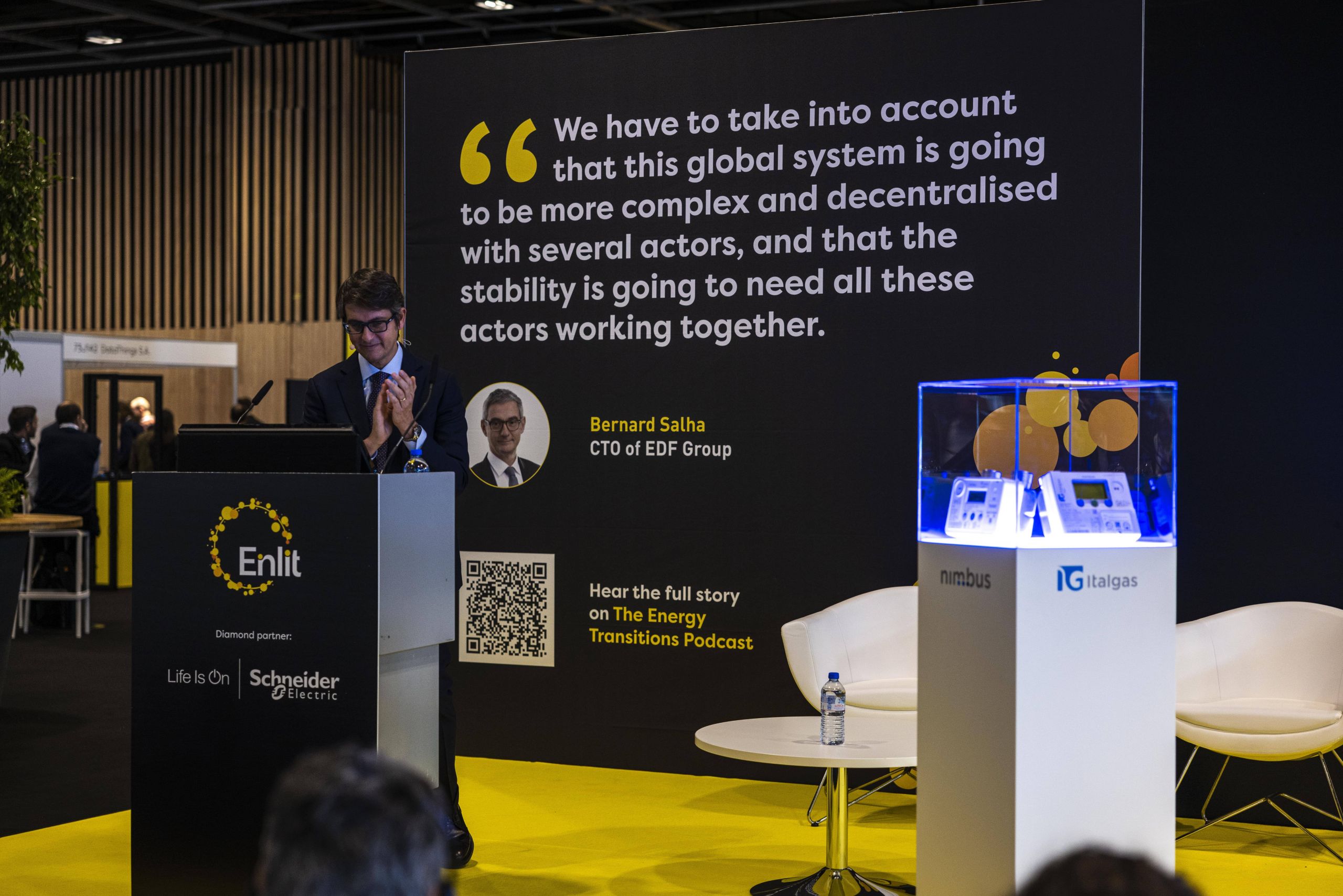 Pier Lorenzo Dell'Orco applaude a convegno Italgas, vicino a schermo con citazione di Bernard Salha, e dispositivo esposto.