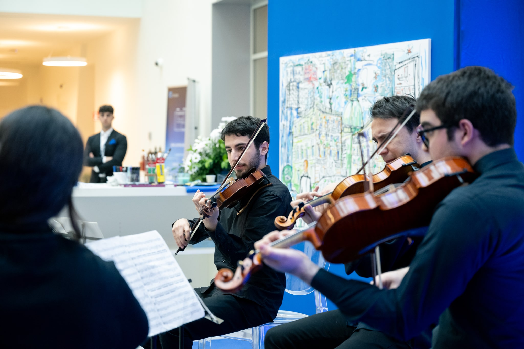 Quartetto di archi suona a evento Italgas Planet Week con mappa sullo sfondo.