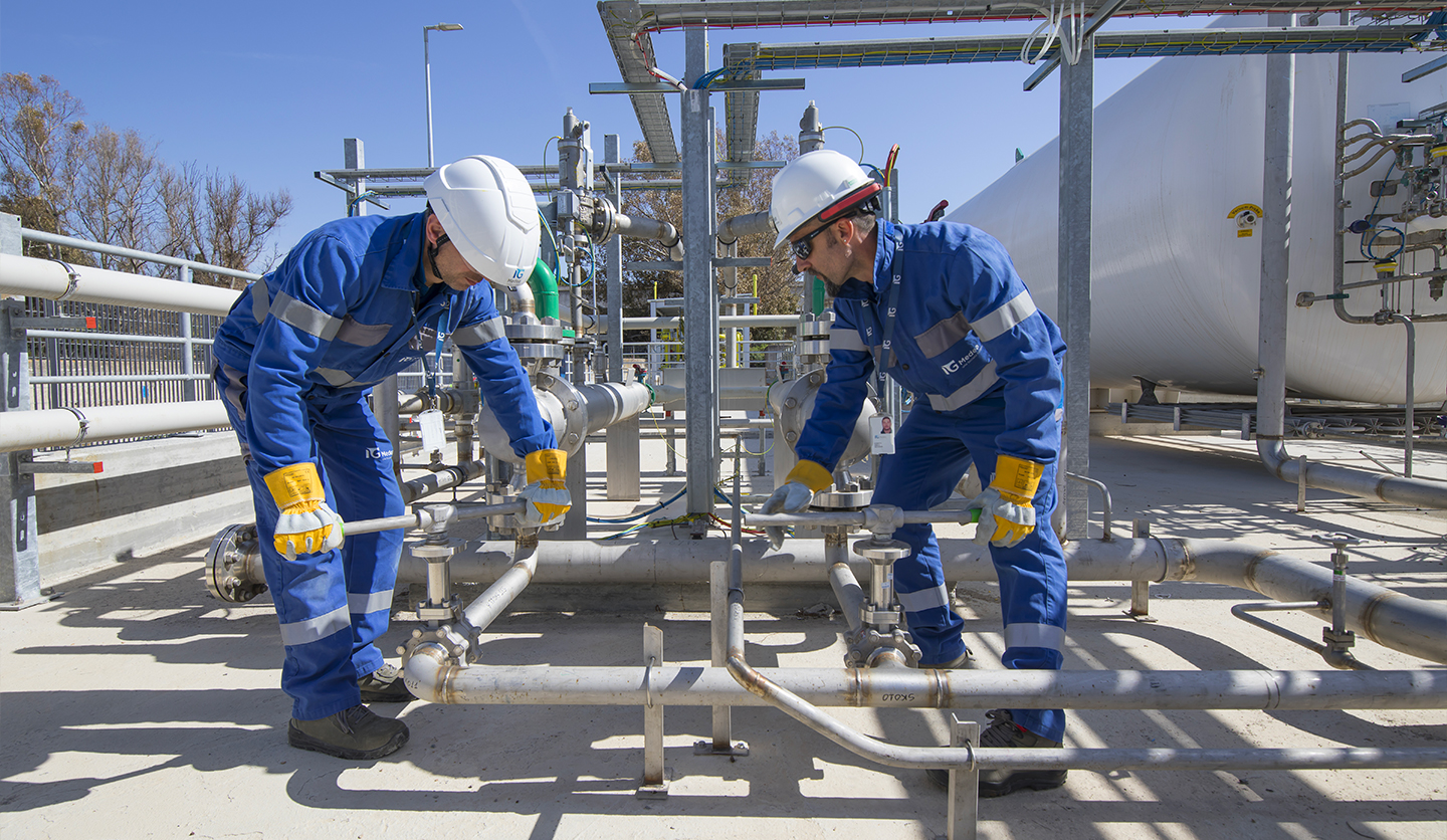 Two Italgas workers work on external pipes, sustainability project in circular economy.