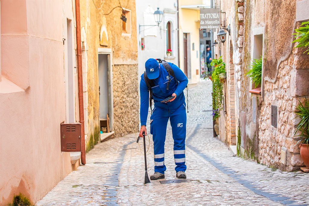 Tecnico Italgas utilizza la lancia dello zaino Picarro per verificare dispersioni di gas su una strada acciottolata.