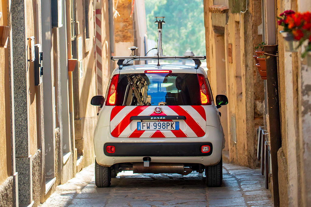 Veicolo Italgas con attrezzatura Picarro sul tetto, parcheggiato in un centro storico in Italia.