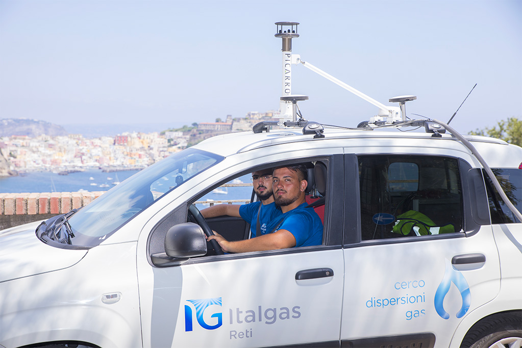 Auto Italgas con attrezzatura Picarro per il rilevamento delle dispersioni gas con due persone a bordo, sullo sfondo il porto della città.